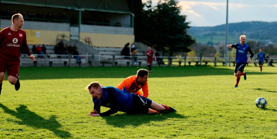 Sombat Penalty Sequence 09: Sombat is down as Pentak slowly goes after the ball, but already expecting some kind of penalty kick. Subject: soccer;football;burgenland;kittsee;Jozef Sombat;Julius Pentek;Andreas Roth