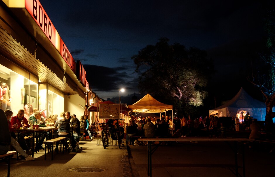 Post-office bar: Kahr/Post Office is turned into an open-air bar, lit by the shop windows. Subject: Kittsee;Kittsee Kirtag;Kirtag;Kahr Kittsee