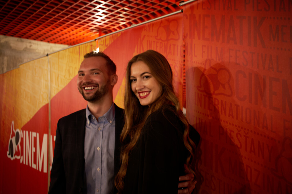 Dominik with Frederique: Guests Dominik and Frederique in front of the 2022 Cinematik banner in Dom Umenie. Dominik distributes films in Slovakia and Czech Republic, while Frederique dances in a Slovak folk dance ensemble when not teaching  or enjoying cinema. Subject: Cinematik