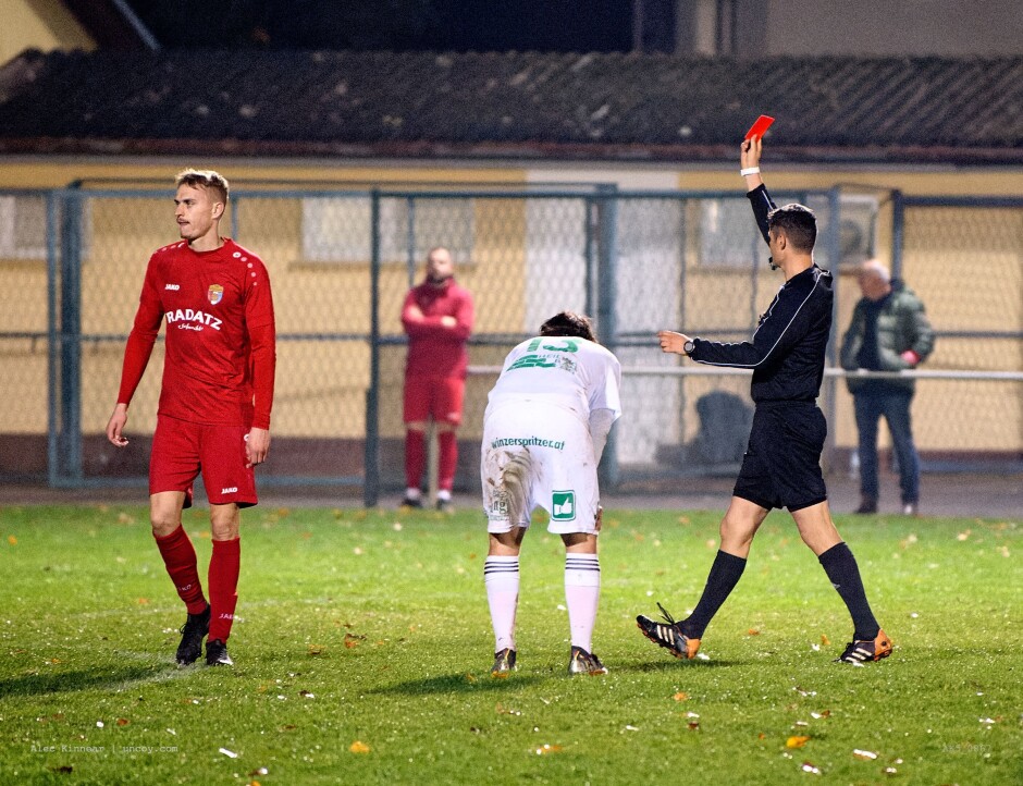 Sazl enjoys a red cart for his trouble.: Referee Manuel Gregorits rewards Thomas Sazl with a well-deserved red card for this two-handed hold. Is it better to be down 3-1 with 10 minutes left in the game or to be down 2-1 with ten players? At the 80 minute mark the goal is worth more than the red card but even if Szombat is left alone one on one with the keeper, there's a good chance the keeper will be able to stop his shot. The red card is a sure thing. Interesting tactical decision. Subject: soccer;football;burgenland;kittsee;SC Kittsee;FC Illmitz;Jozef Szombat;Thomas Sazl;Manuel Gregorits