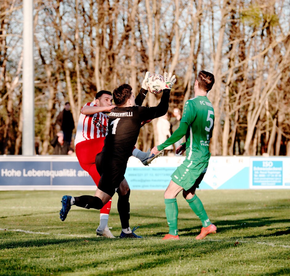 Mustafa Atik competes with FC Winden keeper Roman Ostojic for the ball: There was no real threat here with a a high ball which FC Winden keeper Roman Ostojic easily captured but Kittsee's steady pressure up close gradually knocked Ostojic off his game. Subject: soccer;football;burgenland;kittsee;SC Kittsee;FC Winden;Roman Ostojic;Mustafa Atik;Filip Balazi