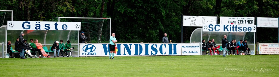 The two sidelines: Johann Thüringer patrols the UFC Pamhagen sideline. In the blue shirt, linesman Harald Mahr. Under the SC Kittsee sign, trainer Manfred Wachter stands. Subject: Kittsee;Pamhagen;SK Kittsee;UFC Pamhagen;soccer;football;Johann Thüringer;Harald Mahr;Manfred Wachter