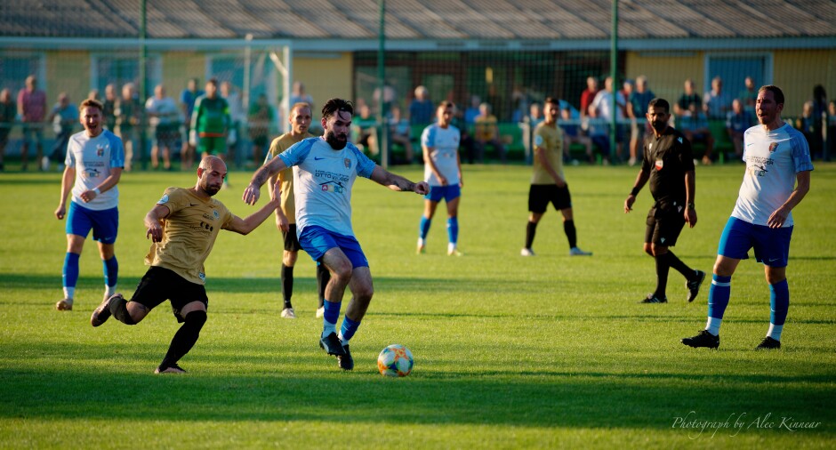 Juraj Fuska takes a pass in front of Juraj Czibula: SC Kittsee didn't seem to be moving at full speed in the heat. Subject: soccer;football;burgenland;kittsee;SC Kittsee;UFC Tadten