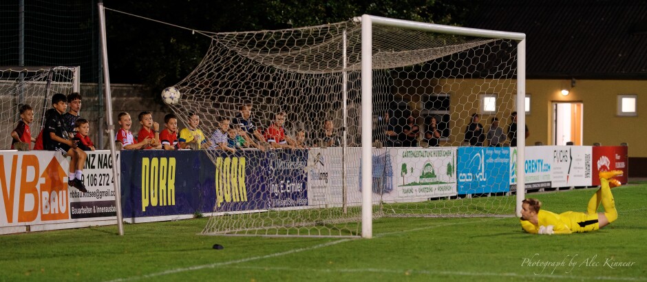 Peter Barinec unable to block Frantisek Nagy's line drive: The Kittsee children cheer and laugh as the game winning penalty hits the back of the net in front of them. Subject: soccer;football;burgenland;kittsee;SC Kittsee;SC Breitenbrunn;Peter Barinec;Frantisek Nagy